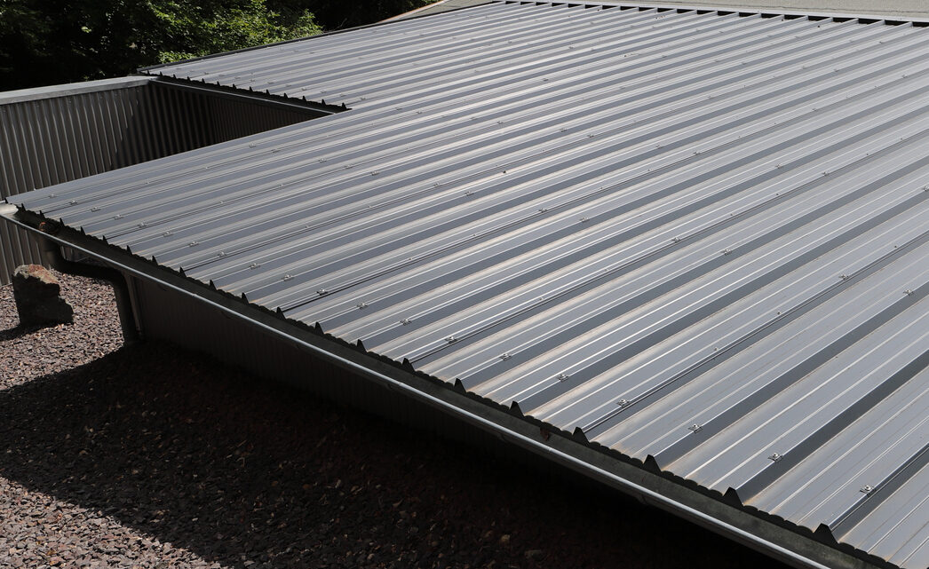 PD home exteriors flat metal roof of new roof installation in Brighton MI, close up image dark gray metal roof.